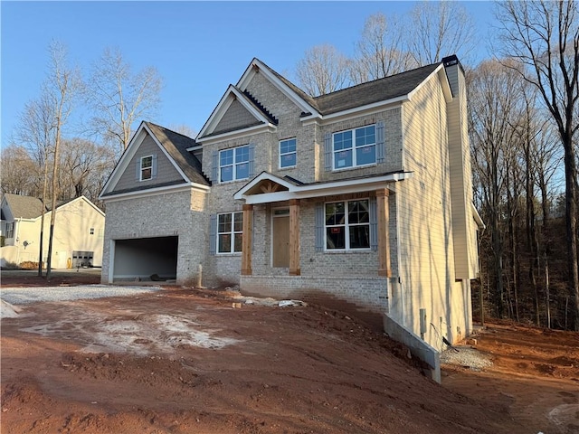 view of front facade with a garage, brick siding, driveway, and a chimney