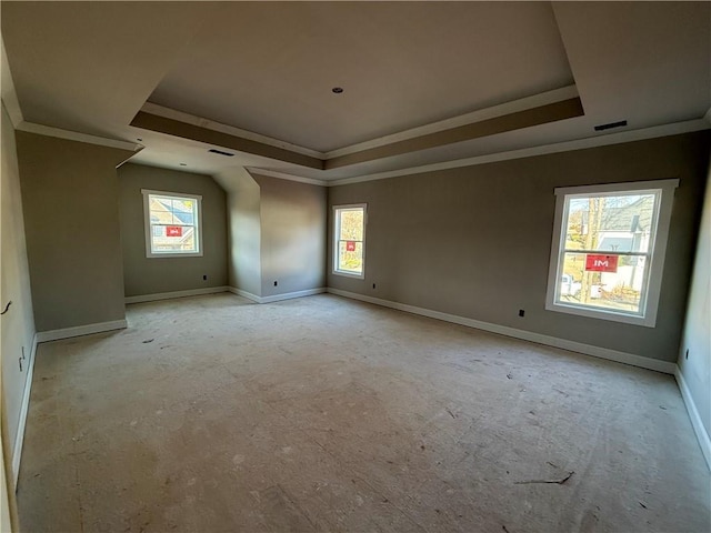 empty room featuring plenty of natural light, a raised ceiling, and baseboards