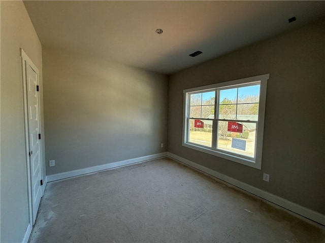 spare room featuring baseboards, unfinished concrete flooring, and visible vents