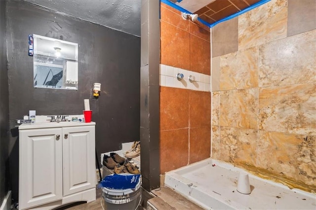 bathroom featuring a tile shower, vanity, and toilet