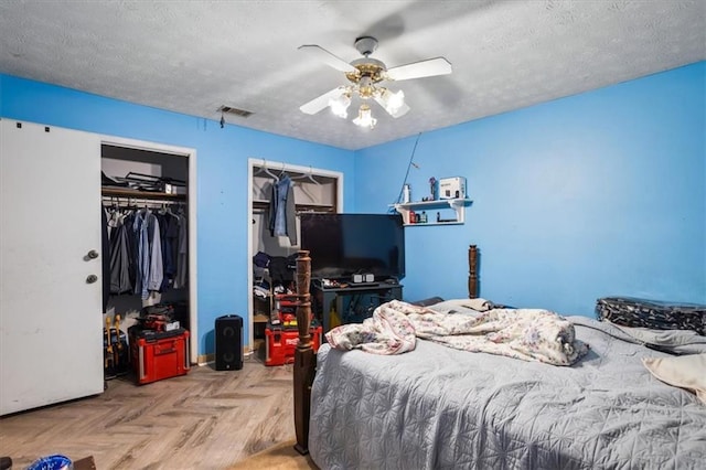 bedroom with ceiling fan, a textured ceiling, and light parquet flooring