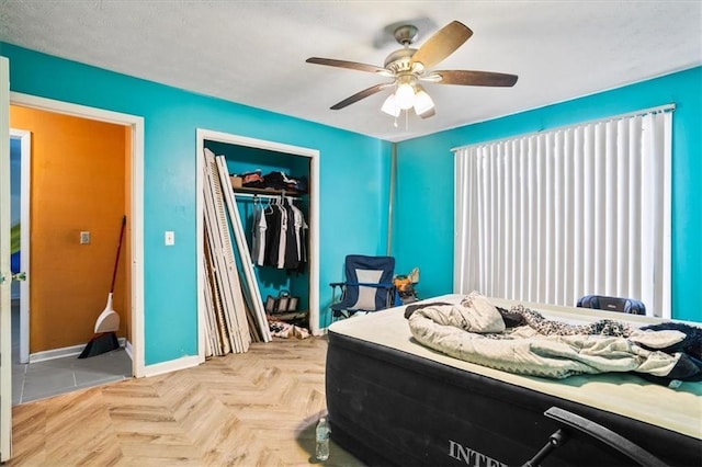 bedroom featuring ceiling fan, light parquet flooring, and a closet