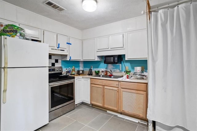 kitchen with sink, light tile patterned floors, white cabinetry, stainless steel electric range oven, and white fridge