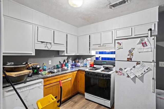 kitchen featuring sink, white appliances, white cabinetry, light hardwood / wood-style floors, and a textured ceiling