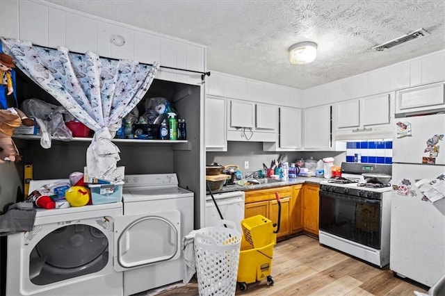 kitchen featuring white appliances, a textured ceiling, white cabinets, separate washer and dryer, and light wood-type flooring