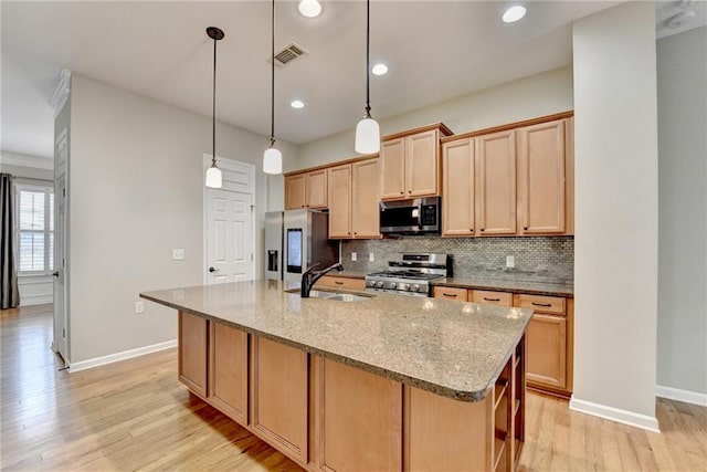 kitchen featuring visible vents, a center island with sink, a sink, stainless steel appliances, and decorative backsplash