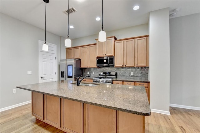 kitchen featuring visible vents, light wood-style flooring, a sink, decorative backsplash, and appliances with stainless steel finishes