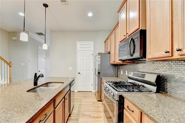 kitchen with backsplash, light stone countertops, light wood-style floors, stainless steel appliances, and a sink