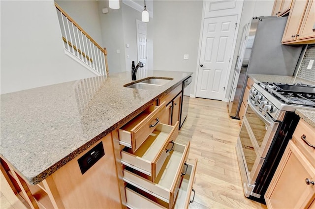 kitchen with range with two ovens, light stone counters, dishwashing machine, light wood-style flooring, and a sink