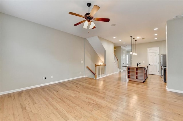 unfurnished living room with a ceiling fan, recessed lighting, baseboards, and light wood-type flooring