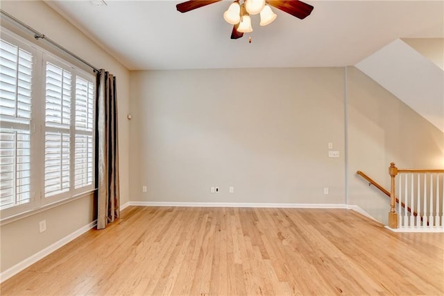 spare room with light wood-type flooring, baseboards, a ceiling fan, and vaulted ceiling