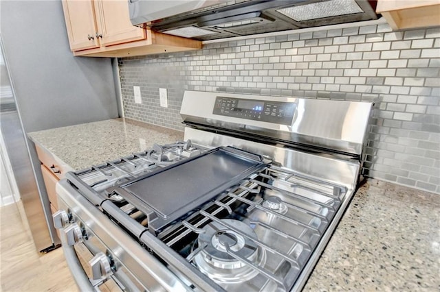 kitchen featuring backsplash, gas range, and light stone countertops