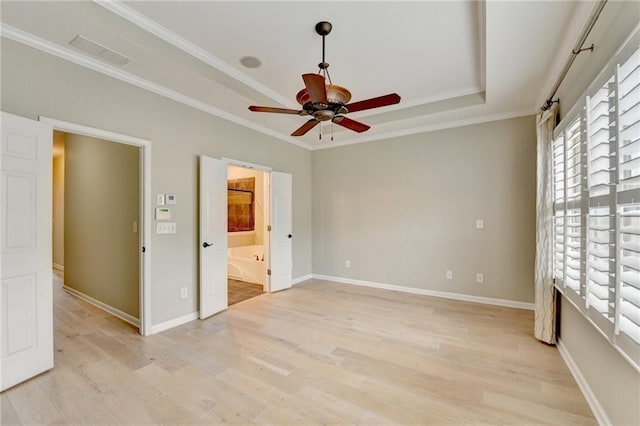 unfurnished bedroom featuring crown molding, baseboards, light wood-type flooring, and a tray ceiling