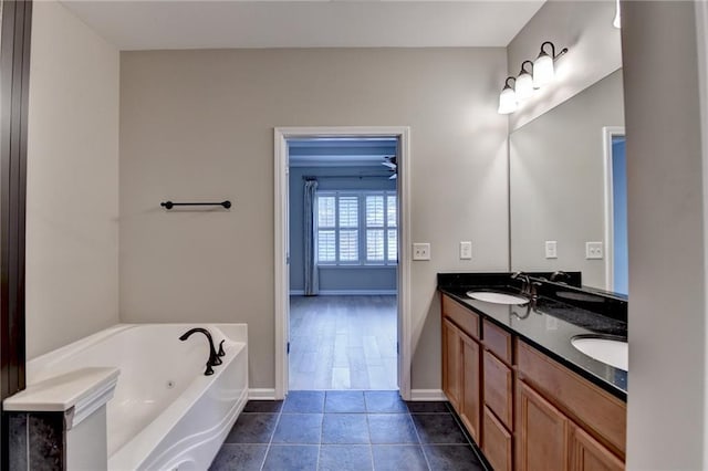 full bath with baseboards, double vanity, a sink, tile patterned flooring, and a jetted tub