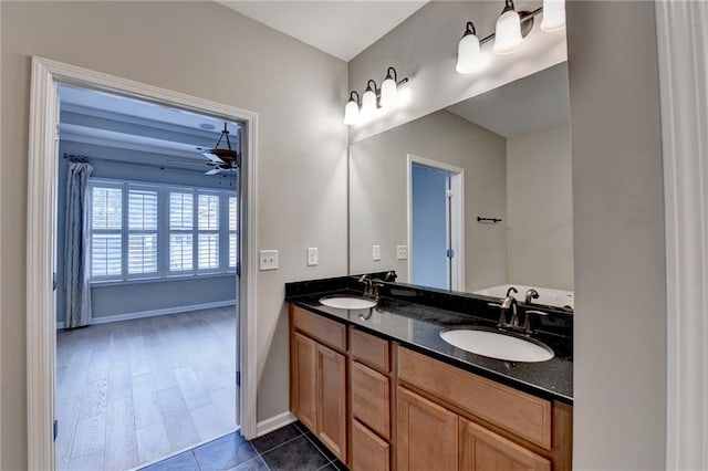 full bathroom with double vanity, baseboards, a ceiling fan, and a sink