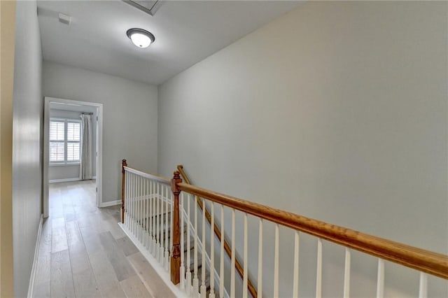 hallway featuring an upstairs landing, light wood-style flooring, and baseboards