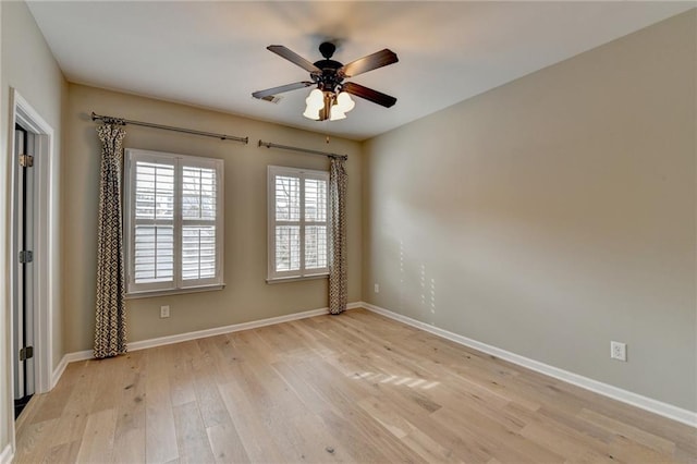 spare room with a ceiling fan, light wood-style floors, and baseboards