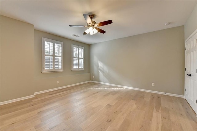 empty room featuring light wood finished floors, visible vents, and baseboards