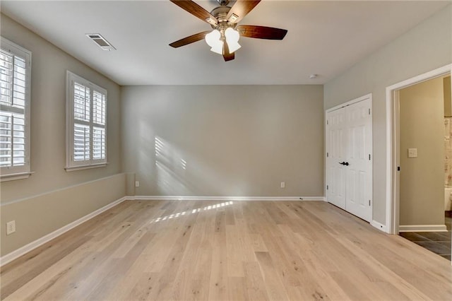 unfurnished room with ceiling fan, visible vents, baseboards, and wood finished floors