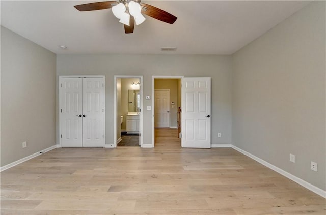 unfurnished bedroom with connected bathroom, visible vents, baseboards, and light wood-style flooring