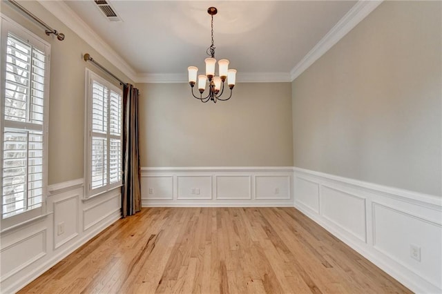 unfurnished dining area with visible vents, light wood-style floors, a chandelier, and crown molding