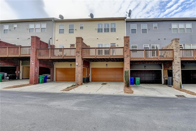 rear view of property with central air condition unit, driveway, and a garage