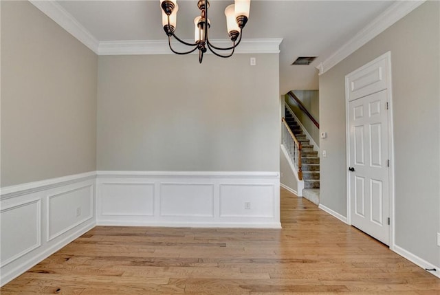 unfurnished dining area featuring stairway, visible vents, light wood finished floors, crown molding, and a chandelier