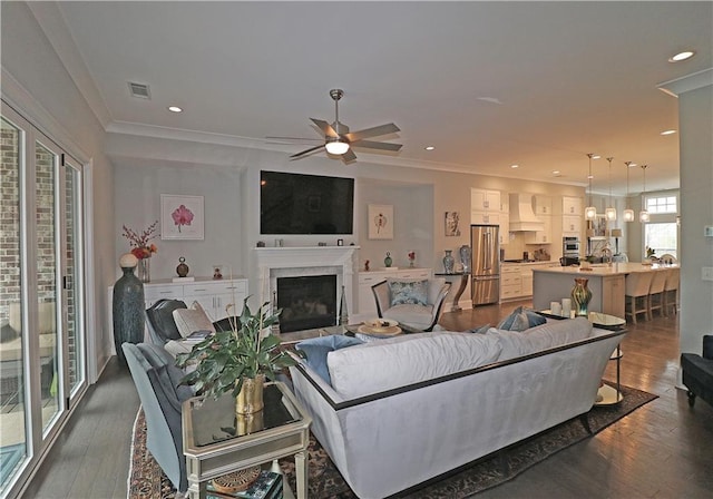 living room with dark hardwood / wood-style flooring, ceiling fan, and ornamental molding