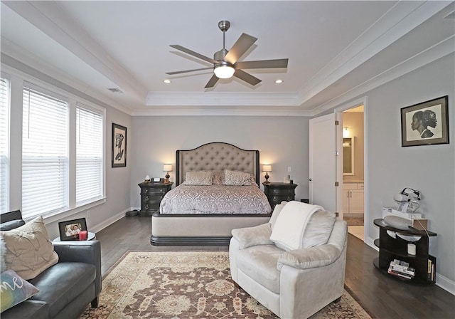 bedroom with ceiling fan, ensuite bath, dark hardwood / wood-style floors, and a tray ceiling