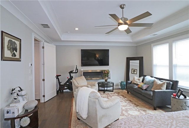 living room with a tray ceiling, ceiling fan, dark hardwood / wood-style floors, and crown molding