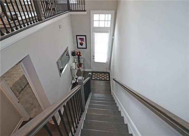 staircase featuring a towering ceiling and dark hardwood / wood-style flooring