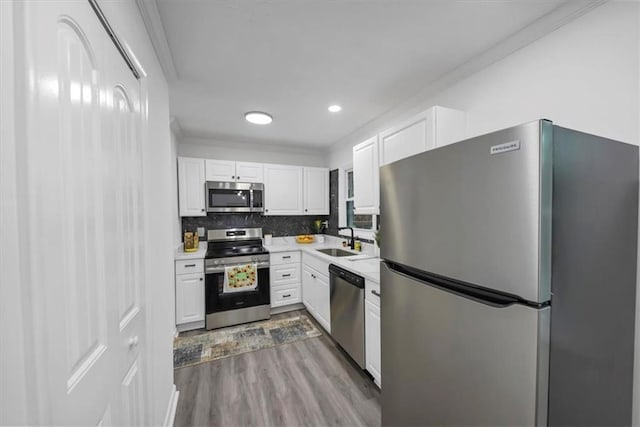 kitchen featuring hardwood / wood-style floors, appliances with stainless steel finishes, white cabinetry, and sink