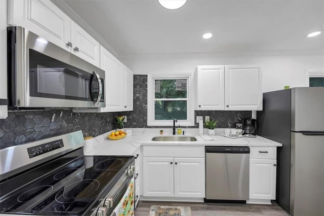 kitchen with light wood-type flooring, stainless steel appliances, white cabinetry, sink, and tasteful backsplash