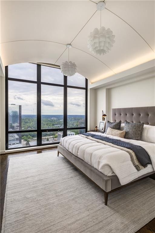 bedroom with multiple windows, hardwood / wood-style floors, expansive windows, and a notable chandelier