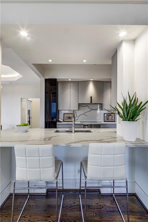 kitchen with gray cabinetry, sink, decorative backsplash, dark hardwood / wood-style flooring, and kitchen peninsula