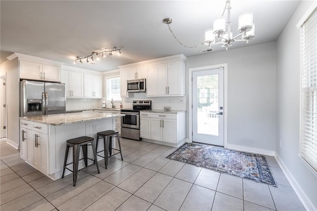 2010 2nd Ave, Decatur, GA 30032 - kitchen featuring stainless steel appliances, a chandelier, light tile patterned floors, white cabinetry, and a kitchen bar