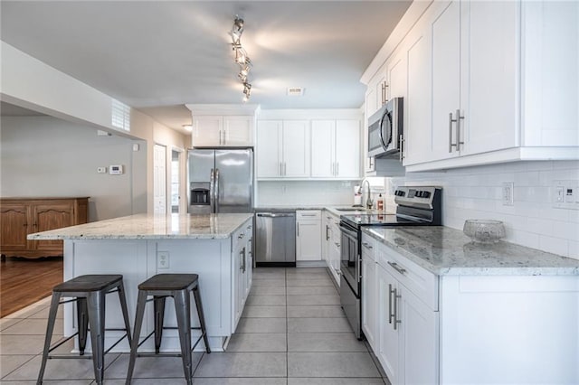 2010 2nd Ave, Decatur, GA 30032 - kitchen with stainless steel appliances, light tile patterned floors, a center island, a kitchen bar, and white cabinetry