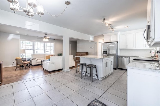 2010 2nd Ave, Decatur, GA 30032 - kitchen featuring appliances with stainless steel finishes, open floor plan, a center island, light tile patterned floors, and light stone countertops