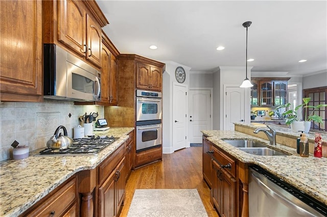 kitchen with hardwood / wood-style floors, appliances with stainless steel finishes, tasteful backsplash, crown molding, and sink