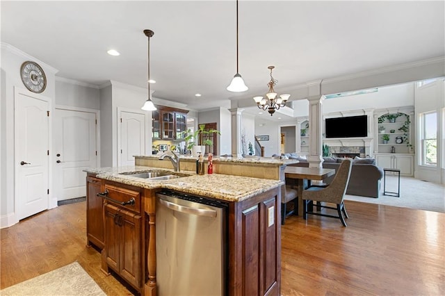 kitchen featuring dishwasher, sink, hanging light fixtures, a kitchen island with sink, and a chandelier