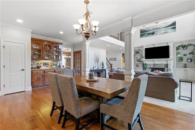 dining room with ornate columns, built in shelves, ornamental molding, and a chandelier