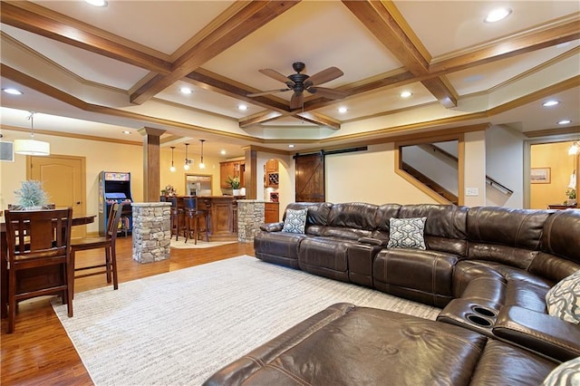 cinema room featuring hardwood / wood-style floors, ceiling fan, crown molding, a barn door, and coffered ceiling