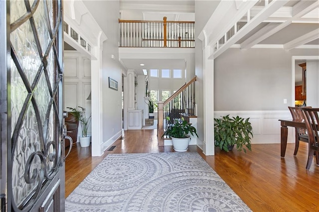 foyer entrance with a towering ceiling, wood-type flooring, and beamed ceiling