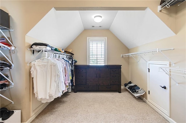 walk in closet with light carpet and vaulted ceiling