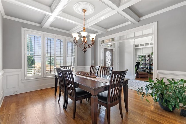 dining space featuring beam ceiling, coffered ceiling, a chandelier, and ornamental molding