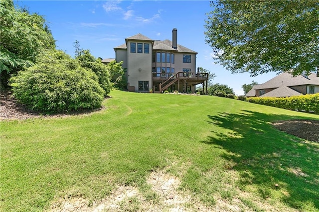 rear view of property with a wooden deck and a yard