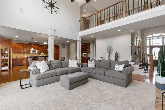 living room with decorative columns, a high ceiling, and light wood-type flooring