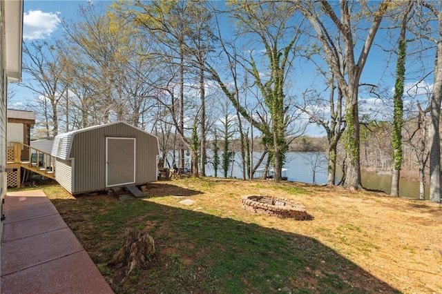 view of yard featuring an outdoor structure, a water view, a fire pit, and a shed