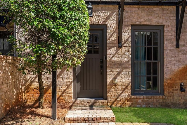 doorway to property with brick siding and fence