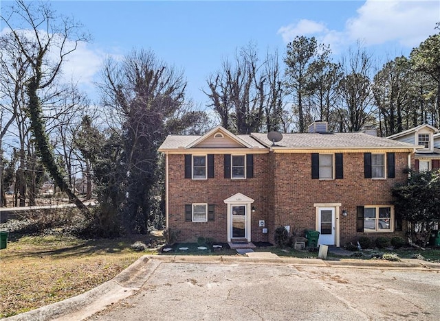 view of front of house featuring brick siding and a chimney